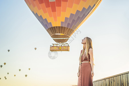 在土耳其卡帕多细亚看热气球的女游客 土耳其概念中的快乐旅行 山顶上的女人享受美妙的景色女士航班自由天空冒险夫妻女孩阳光日出岩石图片