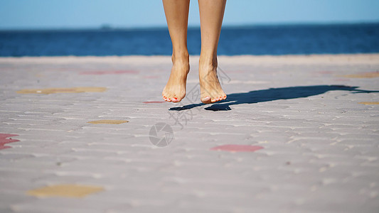 在大海的背景下 女人的腿在赤脚跳舞 夏日炎热的天气下 她会跳起舞来图片