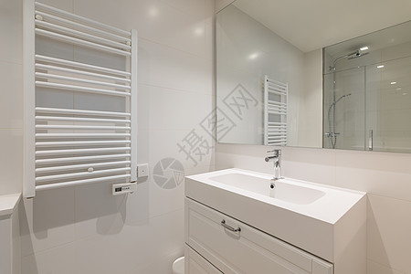 宽敞明亮的洗手间 浴室空虚内装有洗衣盆 一面反映房间对面淋浴的大镜子 天花板和干毛巾暖气散热器背景图片