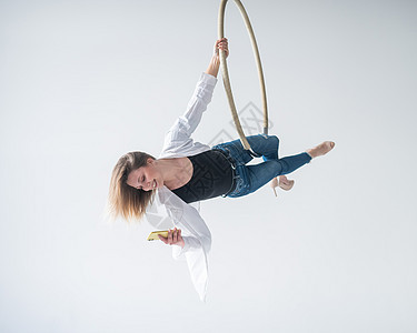高加索女性体操运动员进行空中环球运动和使用智能手机相片艺术身体天线女孩戒指牛仔裤工作室训练运动图片
