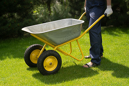 一名手戴手套的年轻人携带着一辆金属马车大车工作园林农场服务独轮车花园场地植物施肥图片