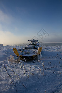 坐在雪覆盖的风景中的老雪车摩托运动海岸太阳运输日光阳光乐趣天气旅行图片