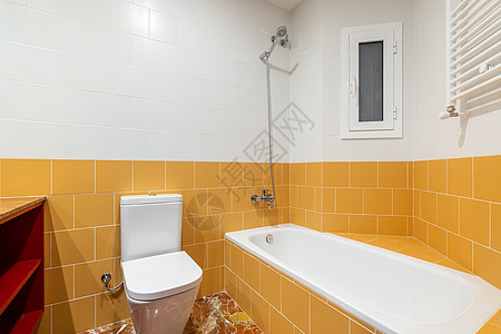 现代明亮的浴室采用华丽的橙色和白色 配有全新的白色浴缸和马桶 浴室有一个小塑料窗 可以让新鲜空气流通 抽象图案房间瓷砖地板背景图片
