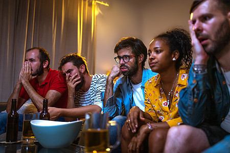 一群朋友在电视上看橄榄球赛 因为球队输了而感到焦虑和悲伤图片