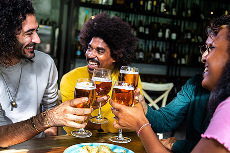 多种族快乐的朋友们在酒吧敬酒 喝啤酒庆祝时享受着饮料图片