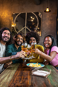 在一个酒吧里快乐的多种族朋友 在看摄影机用啤酒烤面包 垂直图像图片