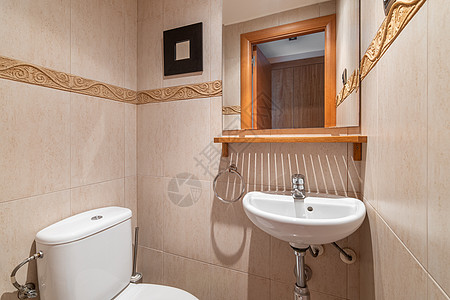 带马桶和洗脸盆的小浴室 墙上的镜子可以看到一扇开着的门 房间的墙壁是用瓷砖装饰的 颜色漂亮细腻 装饰有明亮的条纹图片
