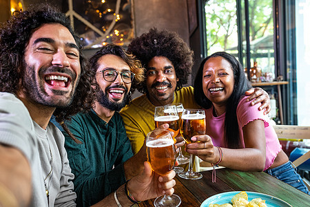 快乐的多种族朋友在一个酒吧烤面包 啤酒拿自拍和手机看相机 (笑声)图片
