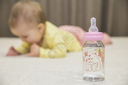 婴儿躺在床边 旁边有一瓶水图片