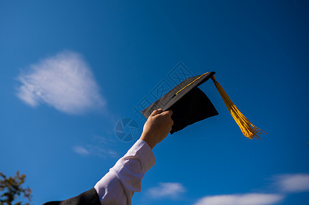 在蓝天上用毕业帽 紧贴着女人的手学士空气学校学生快乐大学帽子女孩手臂文凭图片