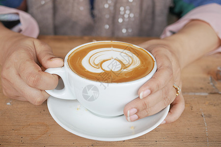 妇女在桌上端着一杯咖啡图片