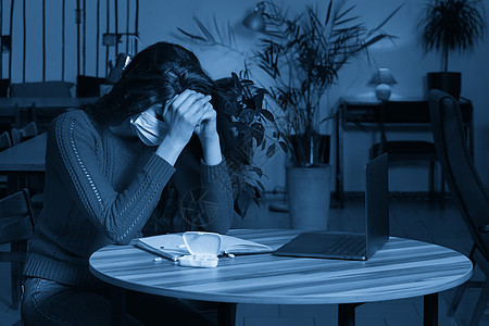 在一张桌上有药片和温度计的患病妇女 在家用笔记本电脑做检疫隔离手术保健自由职业者肺炎女士调子工作疾病蓝色预防口罩图片