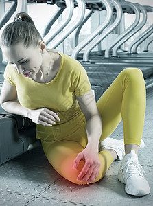 身穿运动服的年轻女性在健身房训练时膝盖疼痛 女孩坐在地板上痛苦地触摸膝盖身体伤害运动女士成人红色体育锻炼创伤医疗事故图片