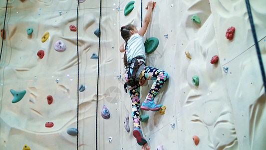 孩子爬上登山专用墙 安全设备七年的女孩在特训垂直墙上从事攀岩闲暇石头操场娱乐灵活性男生学习冒险自由运动图片