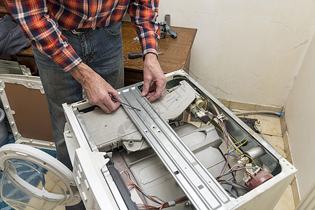 中年男子用工具修理破损洗衣机 家事和家务洗衣店器具工人专家男性丈夫工程师电工机器螺丝刀图片