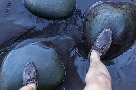雄脚在水面上的绿色石頭上运动冒险靴子男人鞋类石头平衡黑色活动远足图片