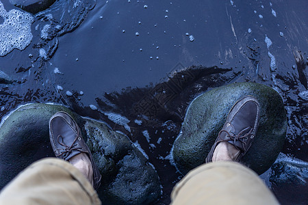 雄脚在水面上的绿色石頭上靴子活动鞋类运动男人海岸石头冒险远足黑色图片