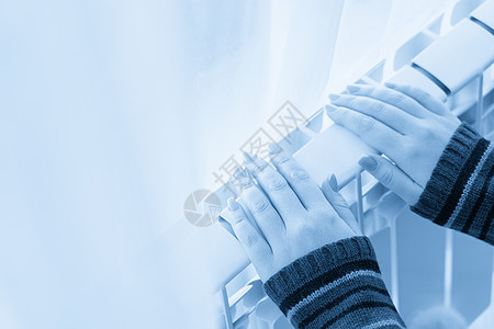 女孩把冷冻的手放在热散热器上蓝色加热女士阀门手指技术活力房子气体房间图片