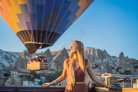 在土耳其卡帕多细亚看热气球的女游客 土耳其概念中的快乐旅行 山顶上的女人享受美妙的景色裙子气球旅游冒险女孩男人日出空气远足假期图片