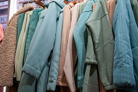在零售店的衣架上穿着多彩妇女服装衣柜衬衫陈列室购物生意夹克架子服装店女性纺织品图片