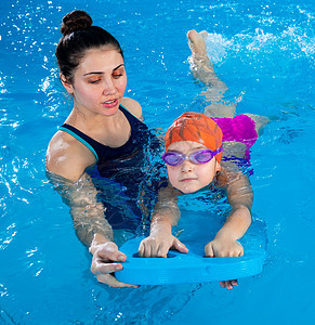 教练教小女孩如何在带泳池浮板的室内泳池游泳木板练习婴儿女孩班级活动孩子游泳者风镜学校图片