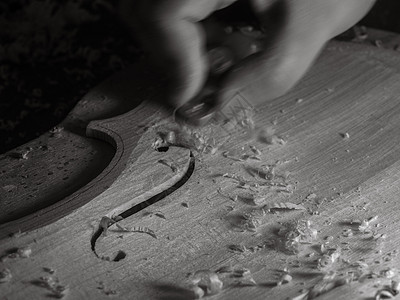 小提琴手在车间用拇指平面和暗光雕刻小提琴板建设职业中提琴工作传统艺术精神产品测量工作台图片