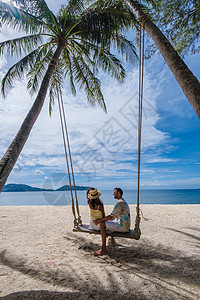 在泰国普吉的棕榈树沙滩上摇摆着一对夫妇旅行热带快乐女朋友男生棕榈男朋友自由蜜月绳索图片