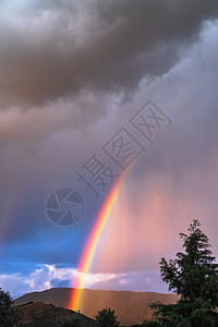 太阳的亮光在暴风天空中破碎 形成一道美妙的彩虹风暴场景戏剧性环境蓝色多云生态耀斑天气晴天图片