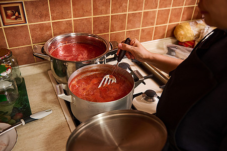 家庭主妇在家中厨房整理熟熟有机多汁西红柿的自制口味纸片时 搅拌煮番茄汁图片