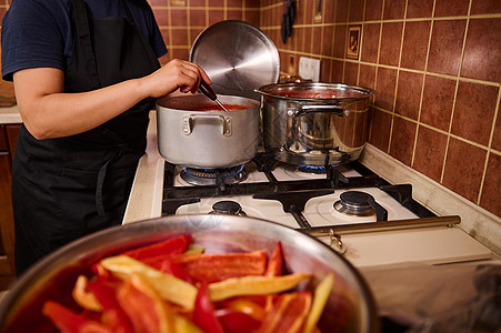 近身家庭主妇 用拉盘搅拌番茄汁在酱锅里煮番茄汁 准备沙拉干菜图片