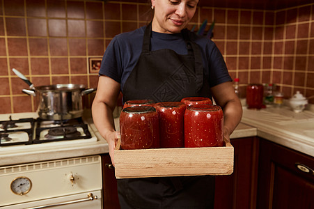 关注用新鲜罐装的自制有机番茄汁或口服卡在箱内 家庭主妇手中的灭菌锡图片
