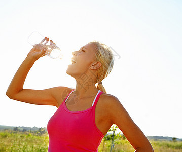 面对严格的锻炼时 补水很重要 一个穿着运动服的漂亮年轻女子从瓶子里喝水图片