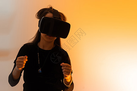 一个戴着虚拟现实眼镜头发的少女看电影或玩电子游戏 用双手表达感激之情 有趣的女孩看着 VR 眼镜 手牵着手互联网模拟小样创新耳机图片