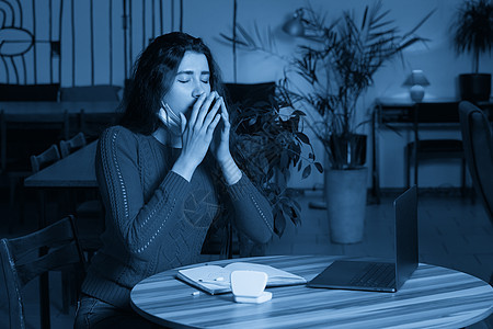 生病的妇女用药丸和温度计打喷嚏 坐在一张桌子上 在隔离隔离区从家里拿笔记本电脑工作流感女士商务互联网疾病危险蓝色人士口罩调子图片