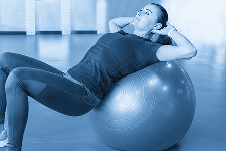 健身房的女生背着球练球 在体育馆练习音调快乐蓝色身体平衡训练女性女士成人女孩图片