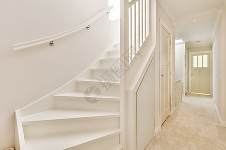 一个白色楼梯 通往走廊的一条白色楼梯大厅门厅沙发窗户地面框架住宅家具桌子木头图片