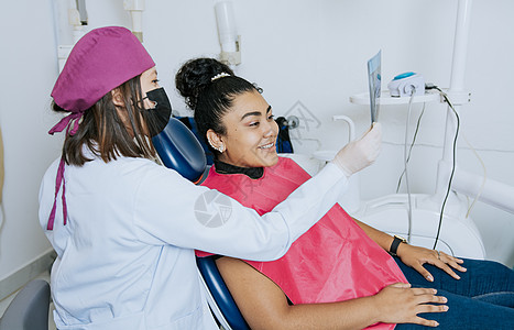 牙医显示病人的 x 光片 牙医与病人一起检查 x 光片 患者与牙医一起看 X 光片 牙医向女性患者展示 X 光片检查的概念图片