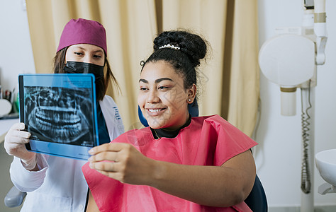 病人和牙医一起看 X 光片 牙医的概念向女性病人展示 X 光片检查 牙医向病人展示 X 光片 有患者的牙医回顾X-射线图片