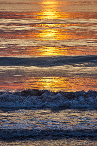 东海岸海面上坠落波浪的详细垂直 金色日出光照亮图片