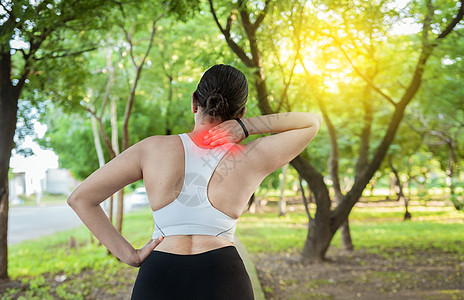 在公园里跑步肩部肌肉疼痛的女人 跑步运动员的肩痛概念 女运动员在户外痛苦地揉着她的肩膀 肩膀疼痛的运动型女性的后视图图片