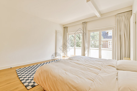 带有床和大窗户的卧室枕头公寓沙发装饰木头家具木地板墙壁地板花瓶图片