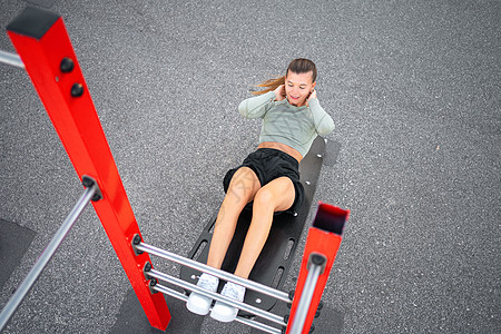 活跃 体格运动的女性在户外健身房上做起立 锻炼和训练体重运动员女孩说谎运动装紧缩女士自重腹部运动机图片