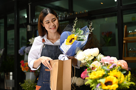 微笑的花店女艺人准备了包花束 以提供给顾客 