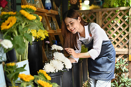 身着围裙的正面女性花卉商在她生锈的花店里摆放鲜花 她们穿着围裙图片