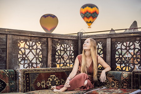 土耳其气球在土耳其卡帕多细亚看热气球的女游客 土耳其概念中的快乐旅行 山顶上的女人享受美妙的景色地质学日出吸引力天空岩石旅游冒险内夫假期气背景