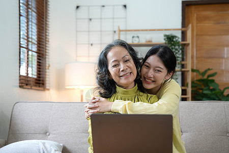 快乐的成年孙女和老祖母坐在现代客厅的沙发上享受谈话的乐趣 微笑的老母亲拥抱年幼的女儿 在家里聊天放松家庭女士孩子女孩奶奶成人幸福图片