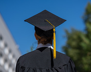 在大学附近穿着毕业礼服的caucasian 女人的视野成就智力投掷手臂证书仪式帽子幸福教育蓝色图片