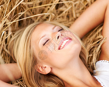 快乐的年轻女人躺在小麦田里 她很幸福图片
