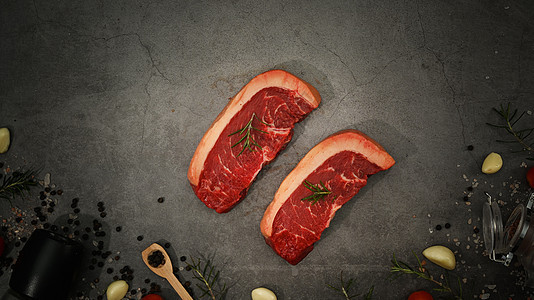 上方是原始的皮卡尼亚肉牛排或香料和黑色石头背景的肉排图片
