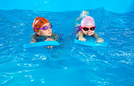 两个小女孩 学会如何在游泳池游泳 用电动滑板游泳练习乐趣朋友们木板训练孩子女孩风镜孩子们游泳板图片